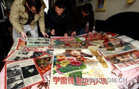 3月1日，房冠龍（中）在家中整理關(guān)于雷鋒的宣傳海報(bào)。