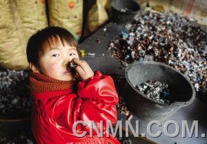 個小朋友在臺州市路橋區(qū)峰江街道一家拆解小作坊內(nèi)玩分揀出來的金屬。